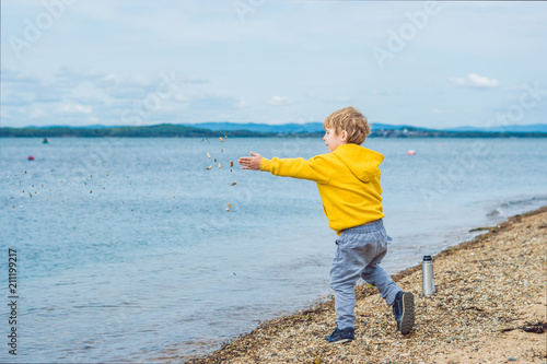 Young boy throwing stones in sea water photo