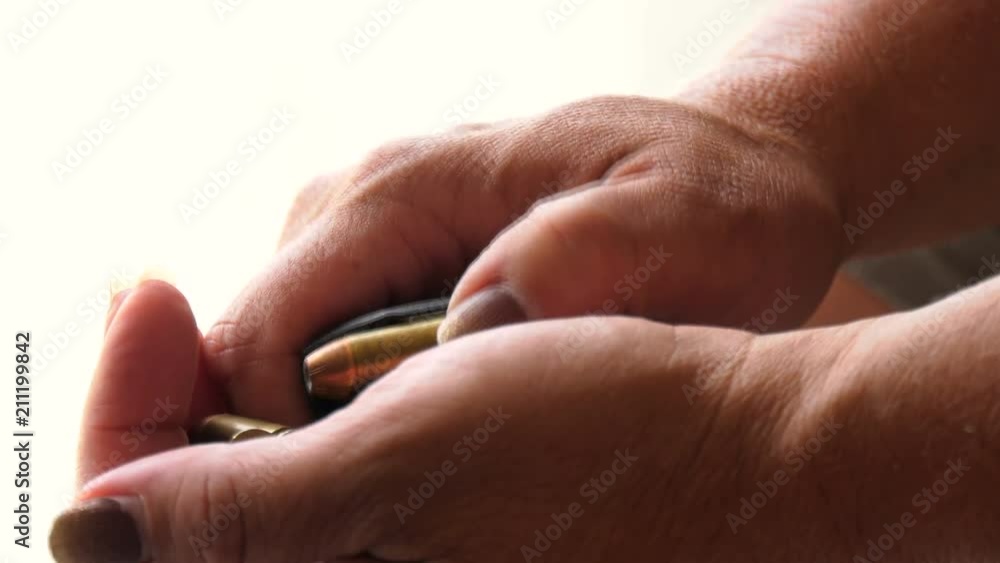 Woman's hand unloading a gun magazine Woman's hand unloading a gun magazine