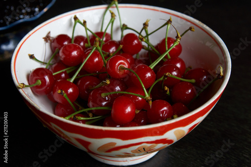 Bowl of fresh red cherries on dark background. Raw Red Organic Cherries food, close-up, outdoors 