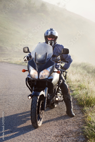 man riding a motorbike on foggy road in early morning