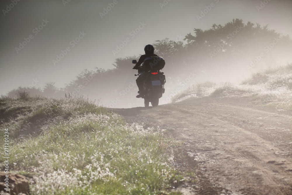 silhouette of a man riding a motorbike on foggy road in early morning silhouette of a man riding a motorbike on foggy road in early morning