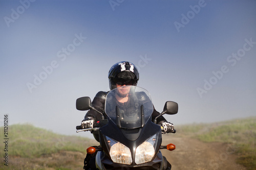 Fototapeta Naklejka Na Ścianę i Meble -  man riding a motorbike on foggy road in early morning