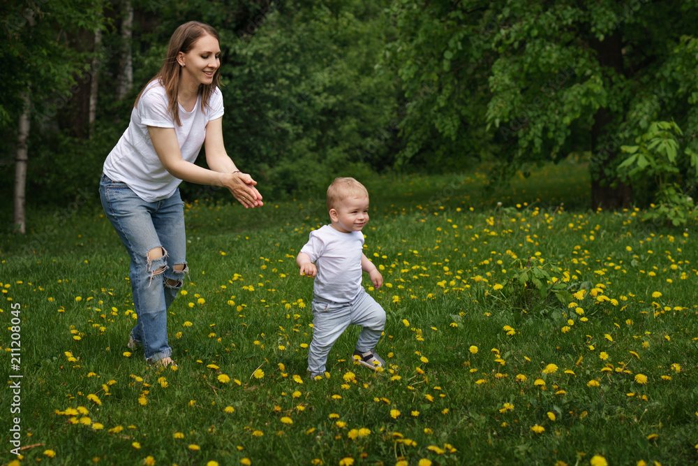 Family. Mom and son are walking around meadow holding hands. Pregnant girl is happy. Little boy learn to walk. Yellow dandelions grow in meadow. Family. Mom and son are walking around meadow holding hands. Pregnant girl is happy. Little boy learn to walk. Yellow dandelions grow in meadow.