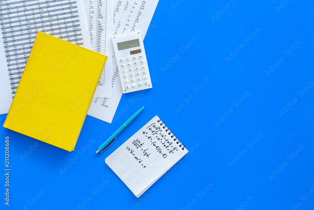 Obraz premium Math homework. Math textbook or tutorial near sheet with numbers, countes, calculator, notebook with formula on blue background top view copy space