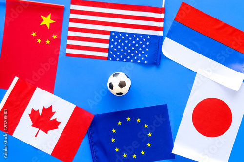 Football championat. American, Canadian, European, Japanese, China, Russian flags and football ball on blue background top view photo