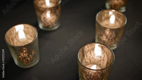 LED Candles flickering  inside of shiny cups on a table