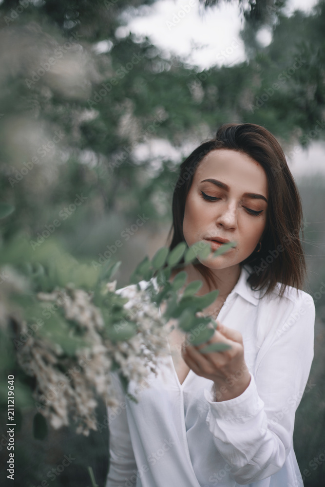 woman in white shirt neat white acacia. girl outdoor woman in white shirt neat white acacia. girl outdoor