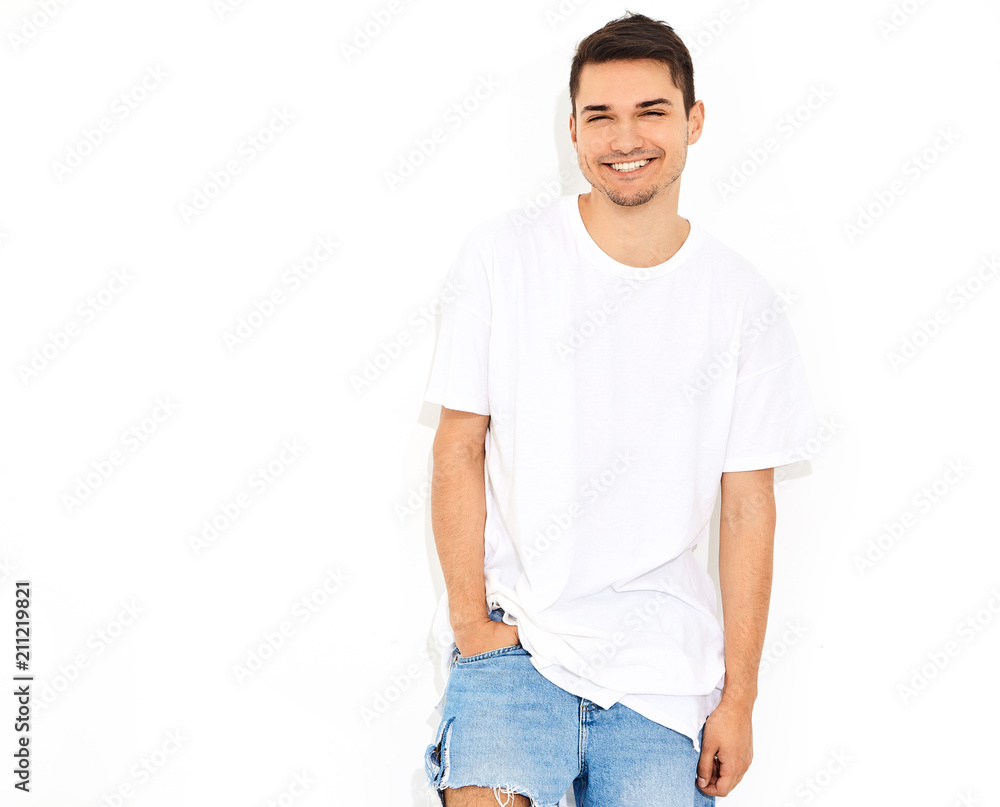Portrait of handsome smiling young model man dressed in jeans clothes and T-shirt posing on white background. Touching his head Portrait of handsome smiling young model man dressed in jeans clothes and T-shirt posing on white background. Touching his head