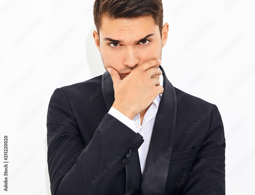 portrait of handsome fashion stylish hipster lumbersexual businessman model dressed in elegant black classic suit. Touching his chin portrait of handsome fashion stylish hipster lumbersexual businessman model dressed in elegant black classic suit. Touching his chin