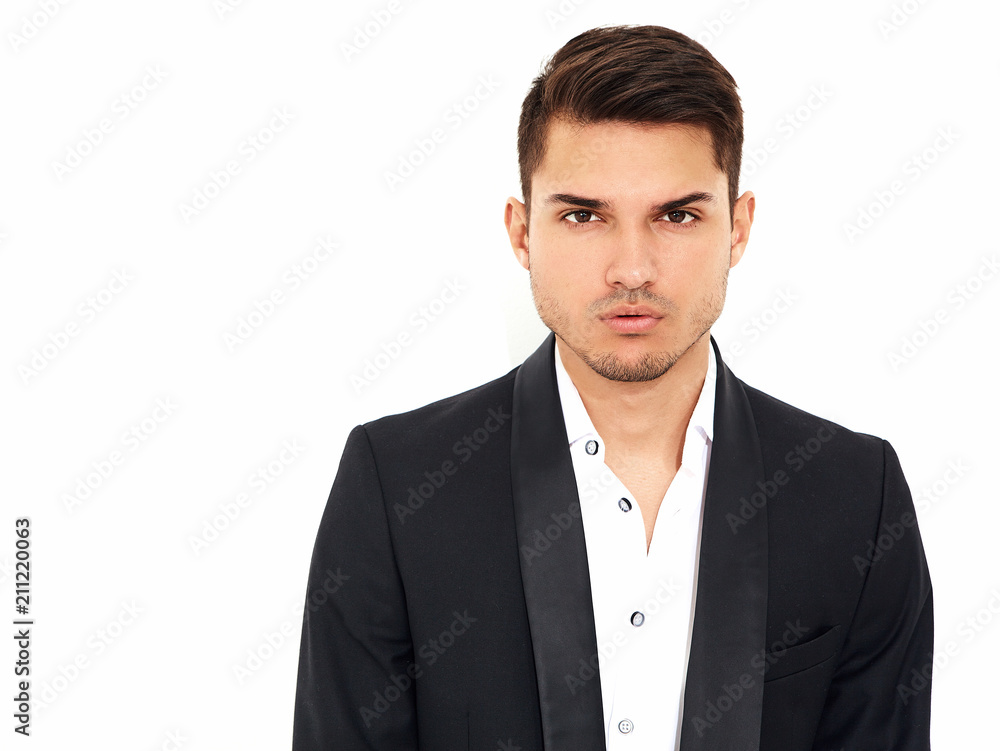 portrait of handsome fashion stylish hipster lumbersexual businessman model dressed in elegant black classic suit posing near white wall in studio. Metrosexual portrait of handsome fashion stylish hipster lumbersexual businessman model dressed in elegant black classic suit posing near white wall in studio. Metrosexual
