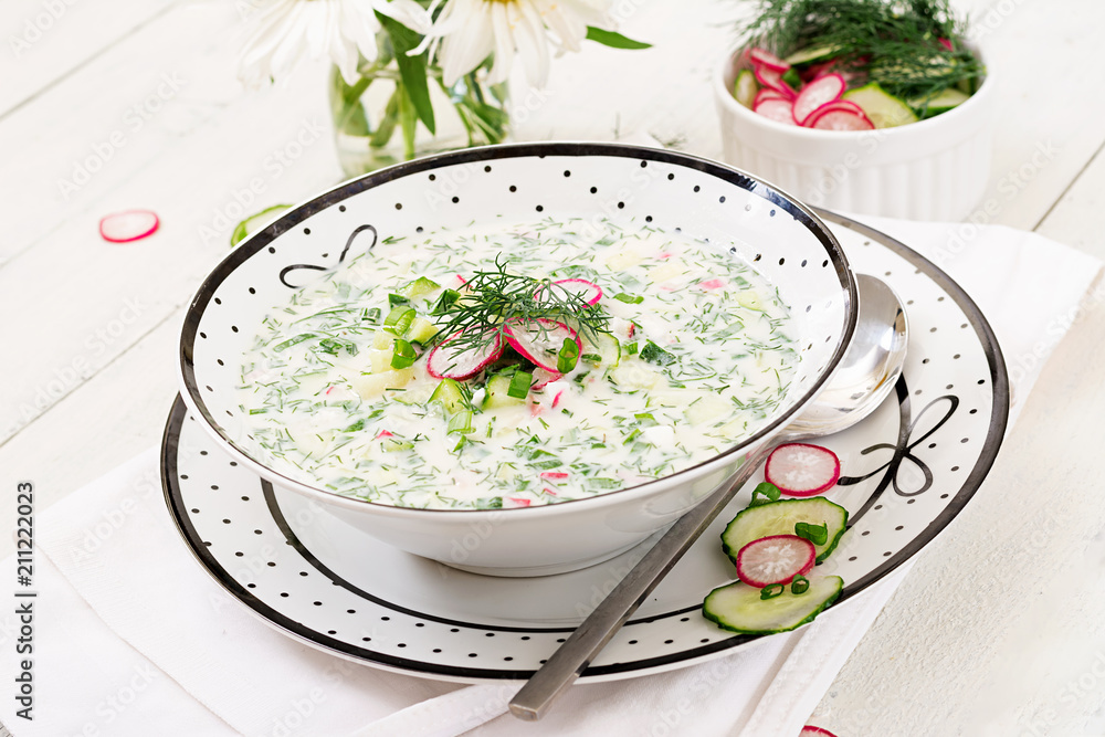 Cold soup with fresh cucumbers, radishes with yoghurt in bowl on wooden background. Traditional russian food - okroshka. Vegetarian meal. Cold soup with fresh cucumbers, radishes with yoghurt in bowl on wooden background. Traditional russian food - okroshka. Vegetarian meal.