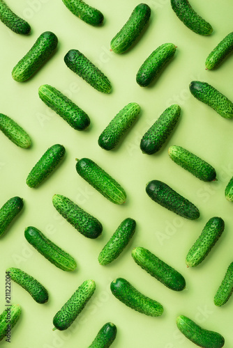 Creative pattern of fresh cucumbers on green background. Top view. Copy space. Minimal design. Vegetarian, vegan, organic food and alkaline meal concept