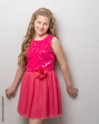 A little girl with long silky hair near the wall.