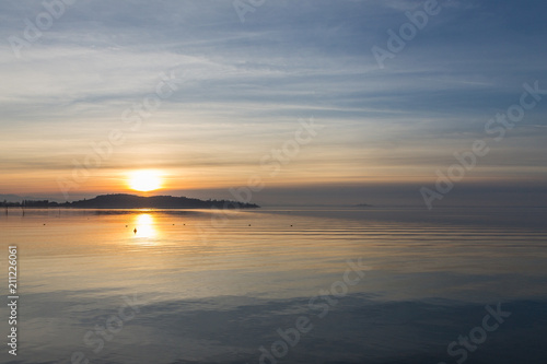 A shoot of a sunset over a lake  with sun coming down behind an island