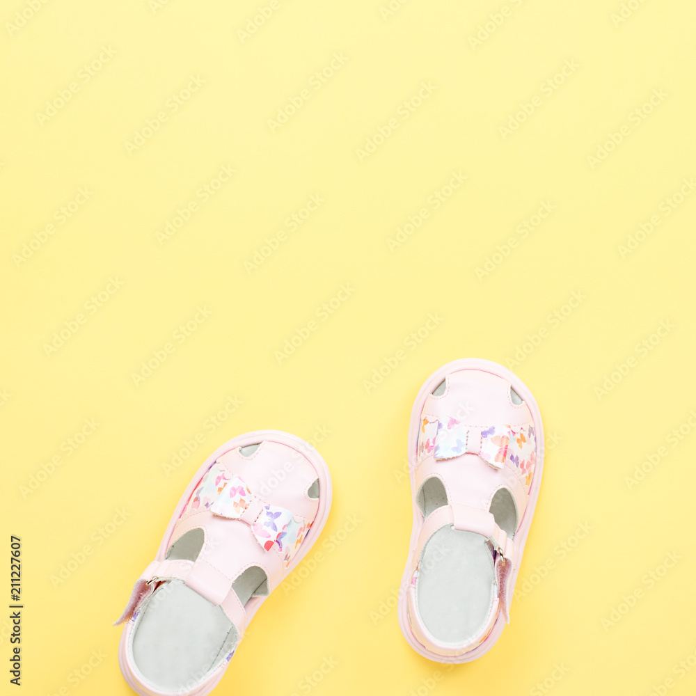 Pink baby girl summer sandals close up on yellow background. Pink baby girl summer sandals close up on yellow background.