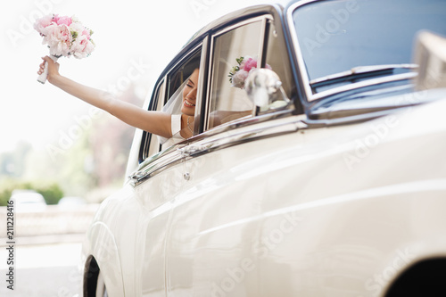 Photography Beautiful bride sits with wedding bouquet in a retro car and has fun