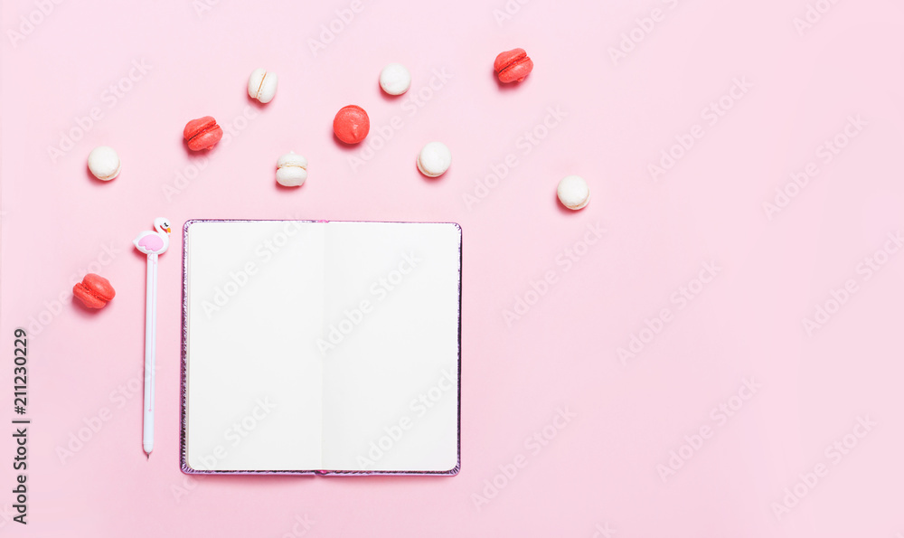 Empty notebook with macarons on pink background Empty notebook with macarons on pink background