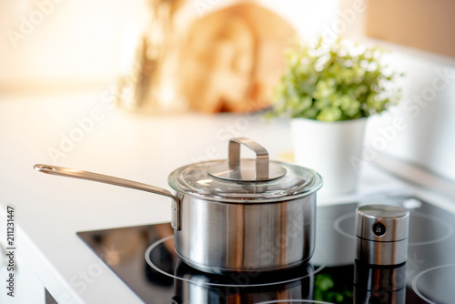 Stainless steel pot on electric stove with kitchen timer in modern kitchen. Cooking utensils concept