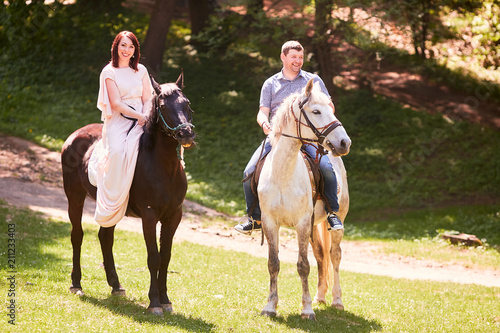 The lovely couple in love riding on horses along park © pyrozenko13