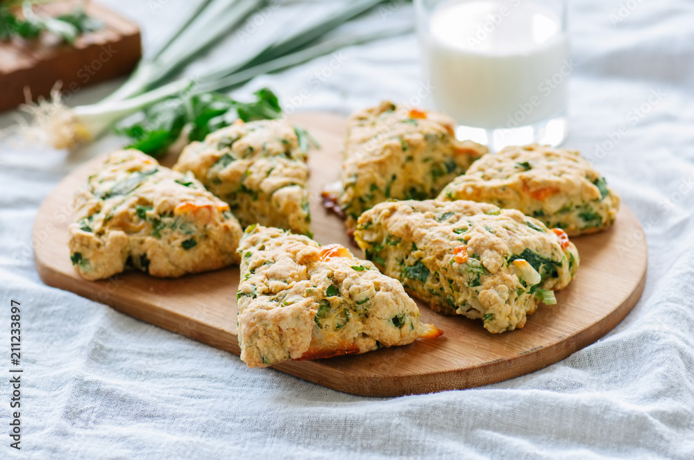 Savory scones with feta mozzarella and green herbs on a wooden board.