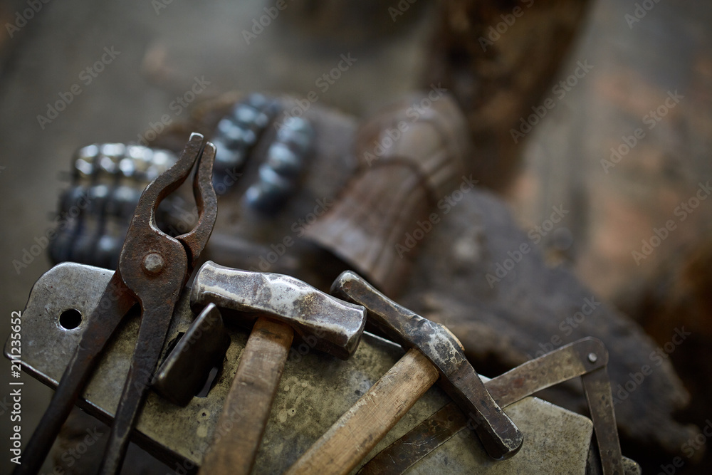Close-up of a blacksmith's hands manipulating a metal piece above his forge, selective focus. Close-up of a blacksmith's hands manipulating a metal piece above his forge, selective focus.