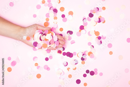 View from above on hand with pink confetti. Party explosion concept.