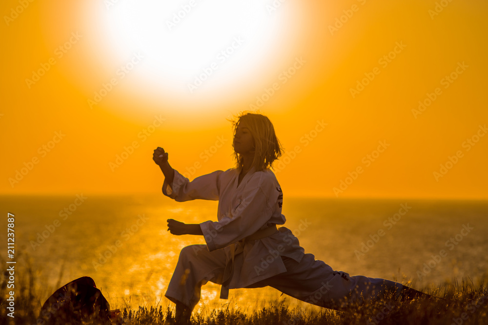 Silhouette of a samurai in a kimono while meditating on the ocean coast, at sunrise. The concept of a healthy lifestyle, unity with nature, meditation.
