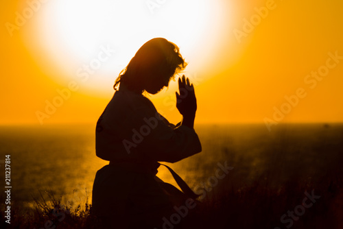 Silhouette of a samurai in a kimono while meditating on the ocean coast, at sunrise. The concept of a healthy lifestyle, unity with nature, meditation.