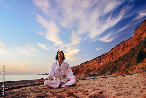 samurai in a kimono while training on the ocean coast, at sunrise. The concept of a healthy lifestyle, unity with nature, meditation.
