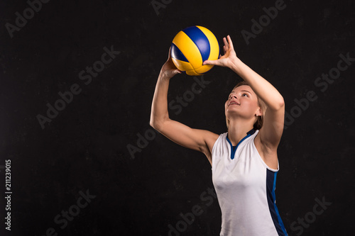Girl playing volleyball on a dark background