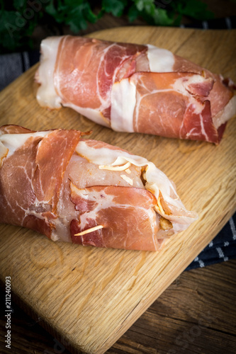 Raw chicken breast stuffed with champignon wrapped with bacon.