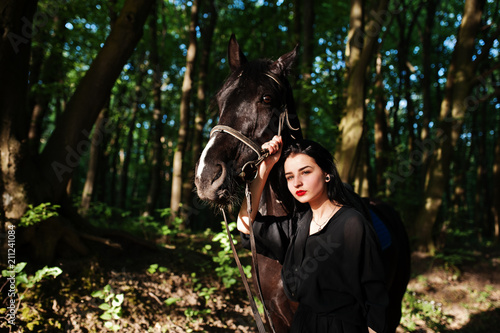 Mystical girl wear in black with horse in wood. © AS Photo Family
