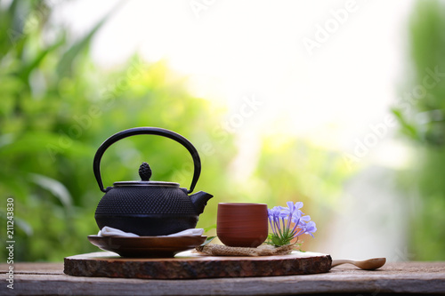 Old black tea pot with brown cup and flower