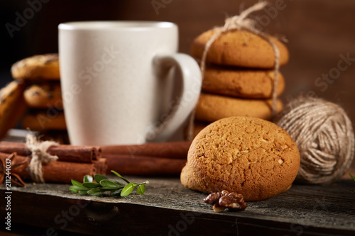 White cup of tea and cookies on a log over country style wooden background, close-up, selective focus