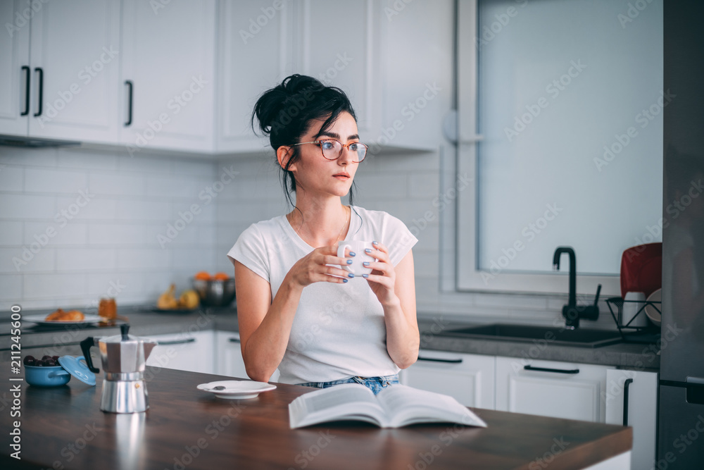 Beautiful young woman reading book in the kitchen Beautiful young woman reading book in the kitchen