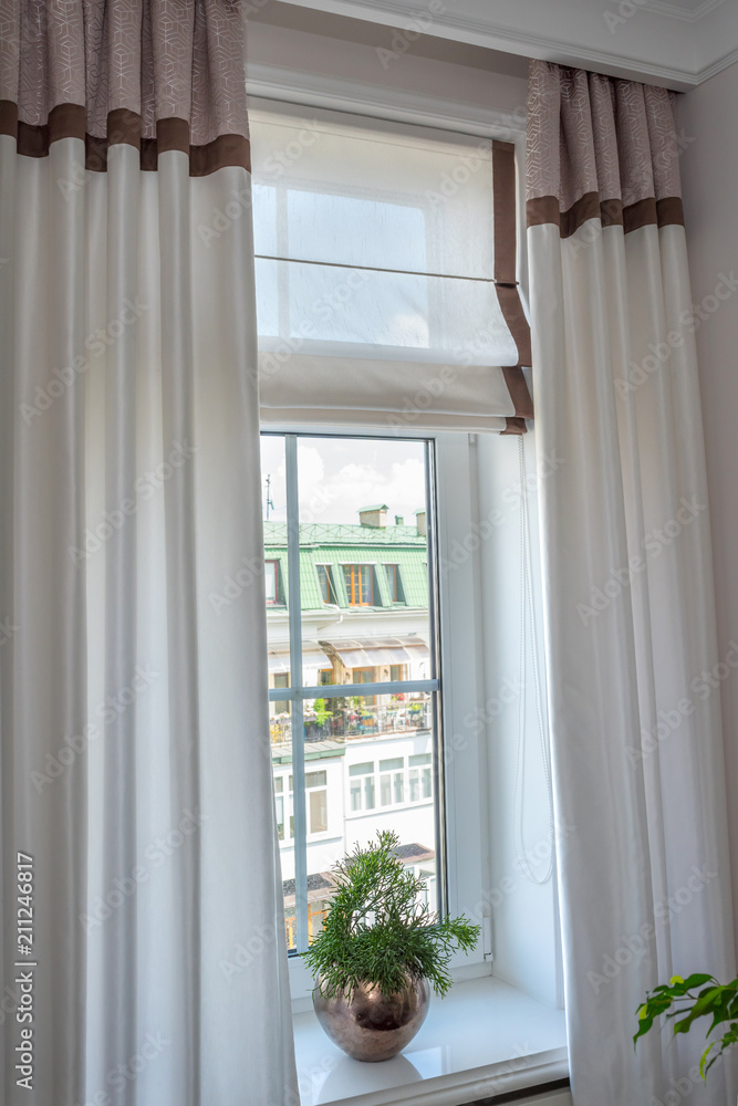 Fototapeta premium Curtains in the interior. From natural light linen, with decorative braid In the room,