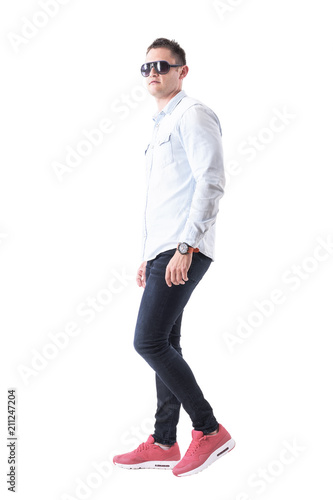 Side view of elegant handsome man with sunglasses in business casual clothes walking and looking away. Full body isolated on white background.  © sharplaninac