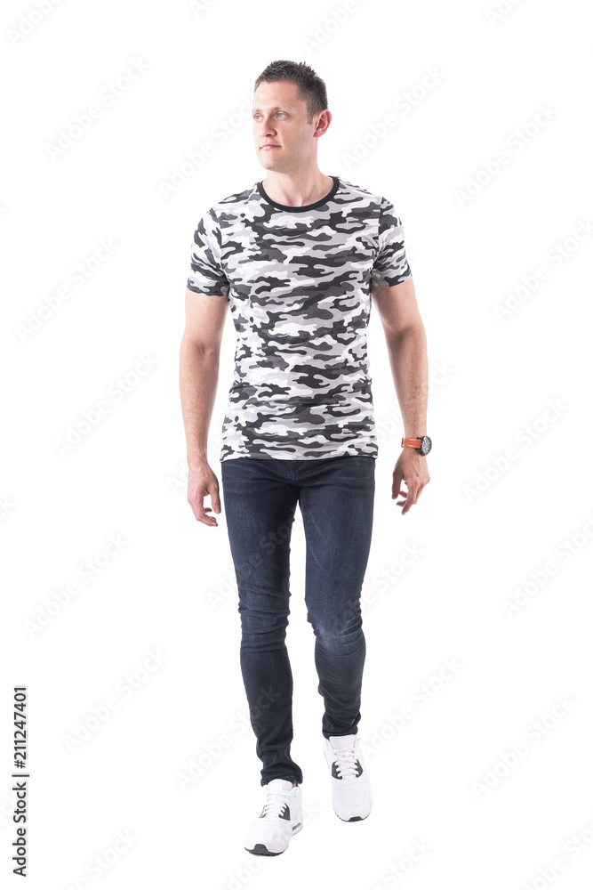 Cool confident handsome man in camouflage t-shirt walking towards camera and looking away. Full body isolated on white background. Cool confident handsome man in camouflage t-shirt walking towards camera and looking away. Full body isolated on white background.