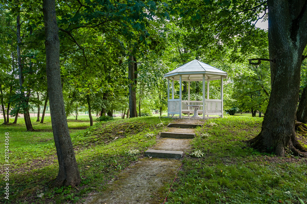 A pavilion in a beautiful garden park. White gazebo in the green summer park. Saka manor. Estonia.