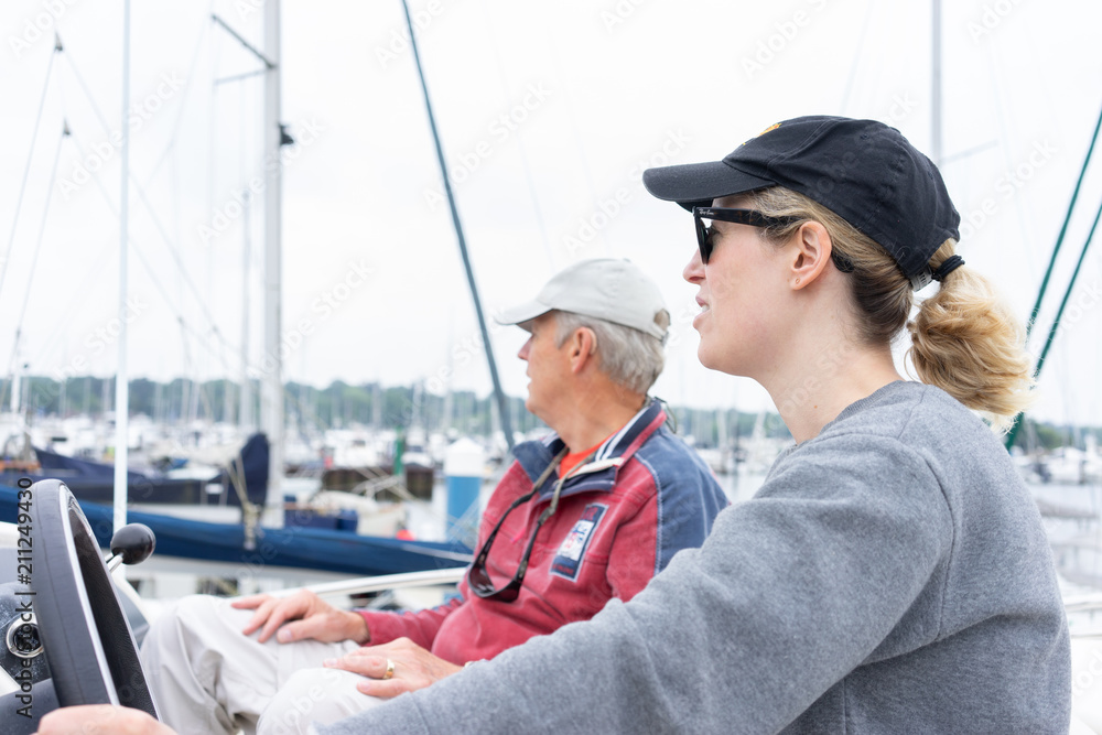 Daughter driving a motor cruiser out to sea with her father