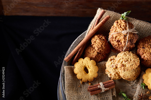 Conceptual composition with assortment of cookies and cinnamon on a wooden barrel, selective focus, close-up