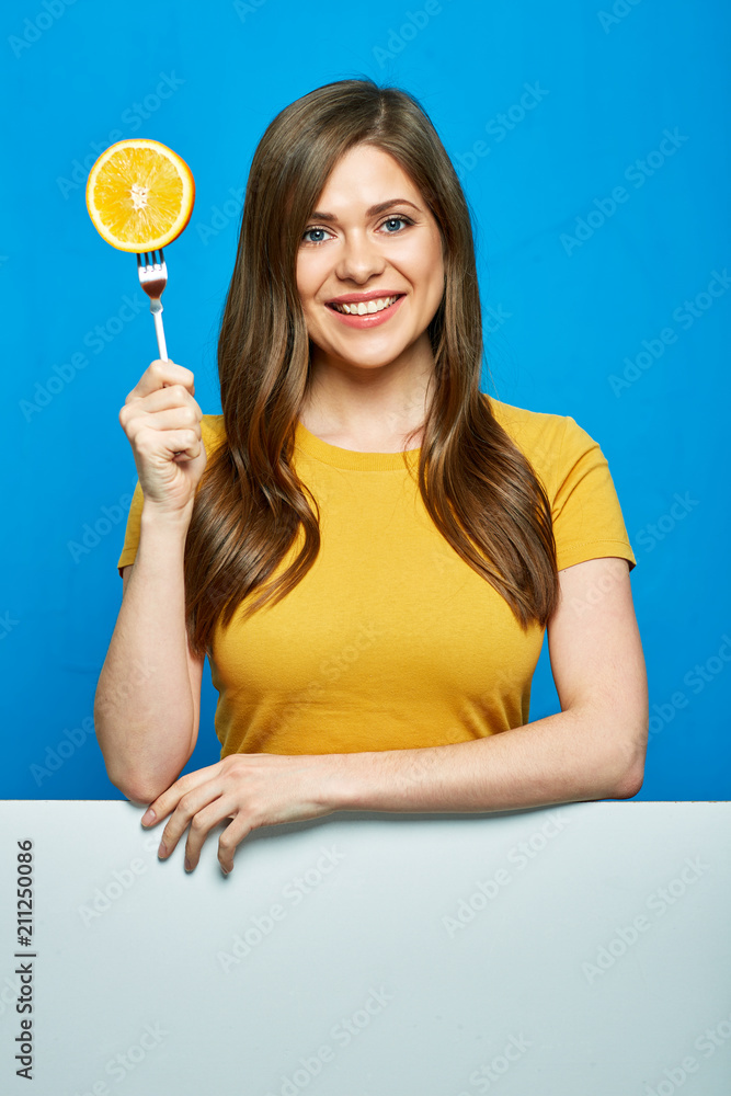 Smiling woman holding orange on fork. Smiling woman holding orange on fork.