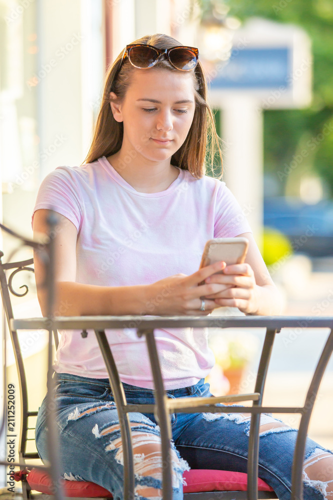 Teenage girl sitting at a table looking at her cell phone