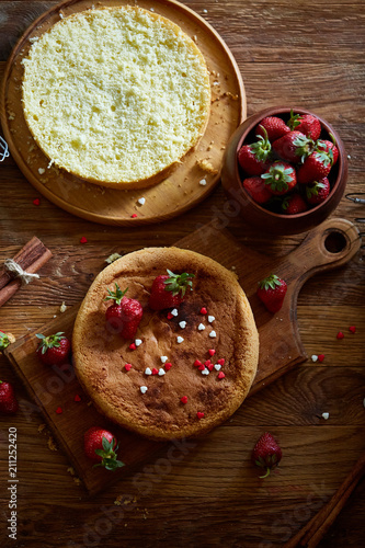 Delicious cake with fresh organic strawberries on cutting board over wooden background, close-up, selctive focus. photo