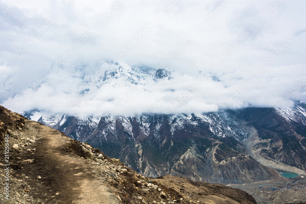 Mountain trail on the background of snowy mountains and clouds, Nepal.