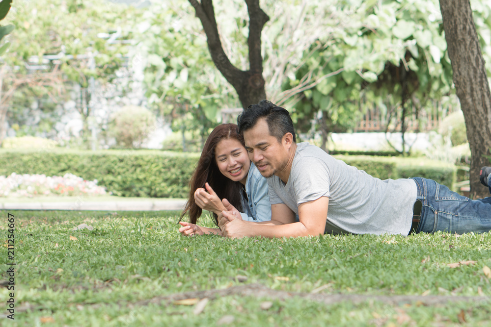 Naklejka premium romantic couple dating in the park. lovers lying on the lawn looking at each other eyes.