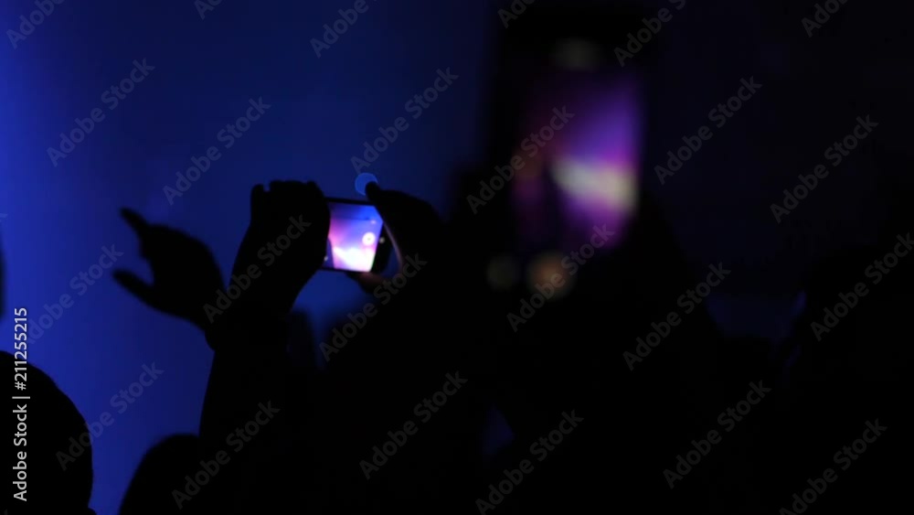 Mobile phone shooting a music concert by spectator silhouette hands in a stage lights Mobile phone shooting a music concert by spectator silhouette hands in a stage lights