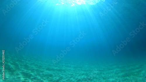 Underwater background with clear blue sea and sandy bottom    