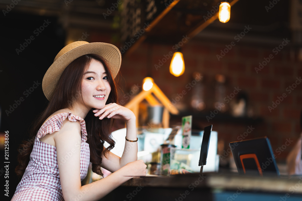 Portrait of cute and beautiful Asian teenage girl smiling in coffee shop with copy space. Cafe culture casual lifestyle, happy traveler woman, weekend hobby activity, or leisure relax holiday concept