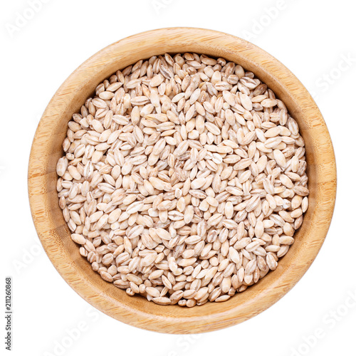 Pearl barley in wooden bowl isolated on white. Top view.